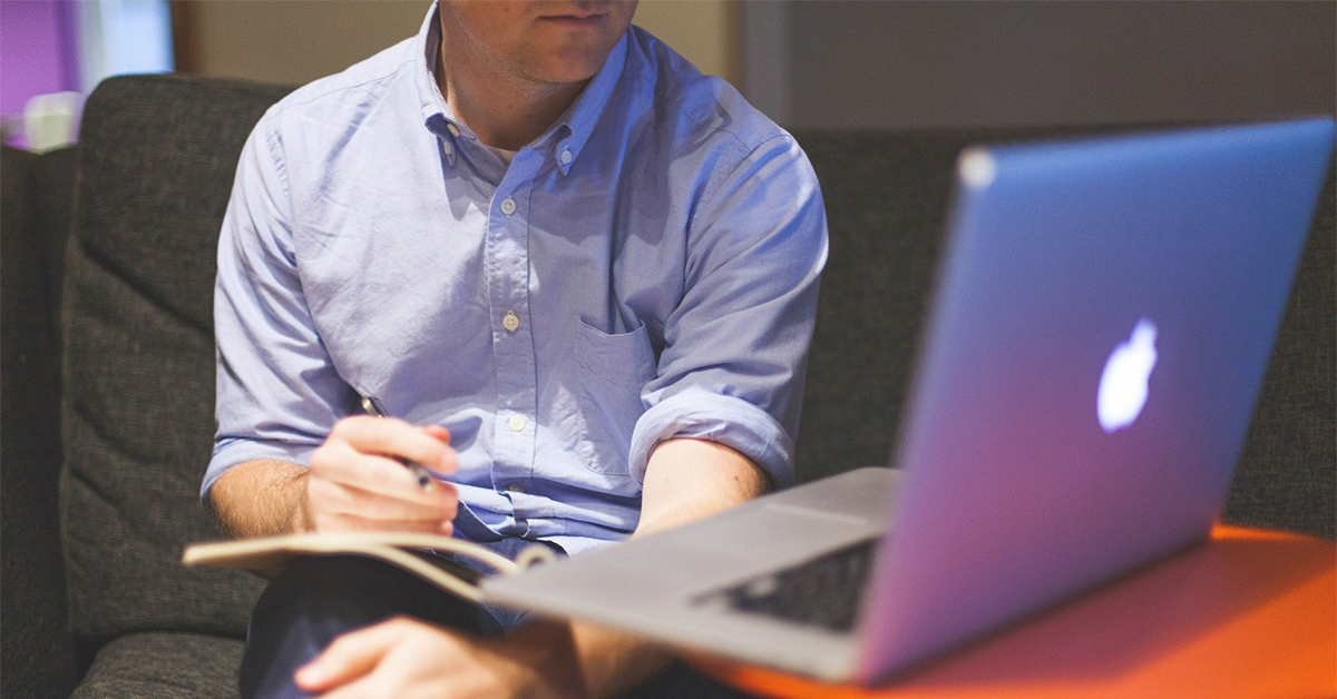 Man taking notes while listening to a session on his computer